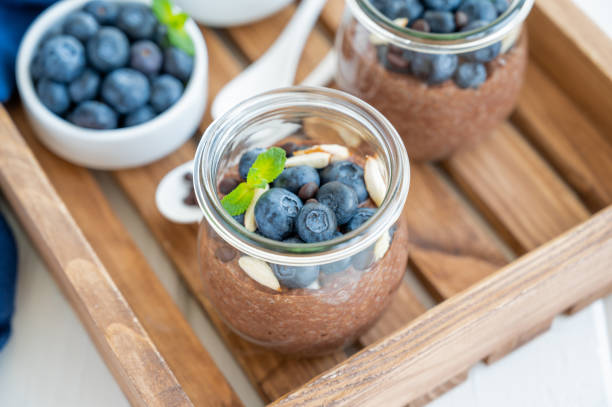 istock Chocolate chia pudding with blueberry, almonds and mint on top in a glass jar on a white wooden background. Healthy food. Copy space. 1314181582