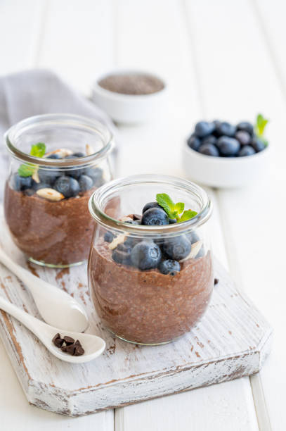 istock Chocolate chia pudding with blueberry, almonds and mint on top in a glass jar on a white wooden background. Healthy food. Copy space. 1314181632