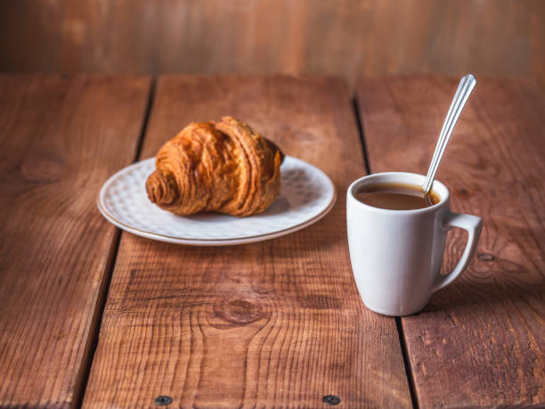 istock Light breakfast with croissant and black coffee in a white mug 1314184191