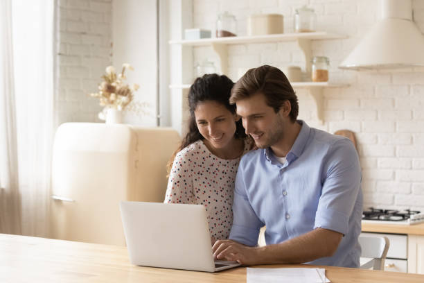 istock Happy young couple using laptop in modern kitchen together 1314187304