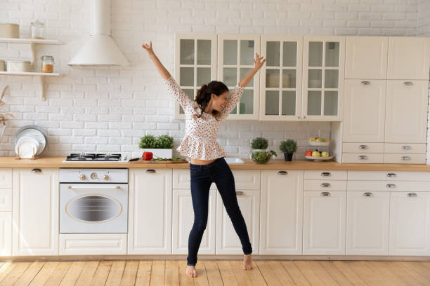 istock Overjoyed young woman dancing, jumping in modern kitchen at home 1314187317