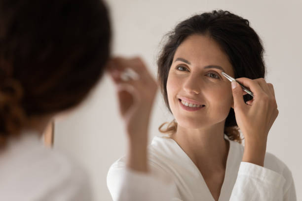 istock Close up smiling woman plucking thick eyebrows with tweezers 1314187334