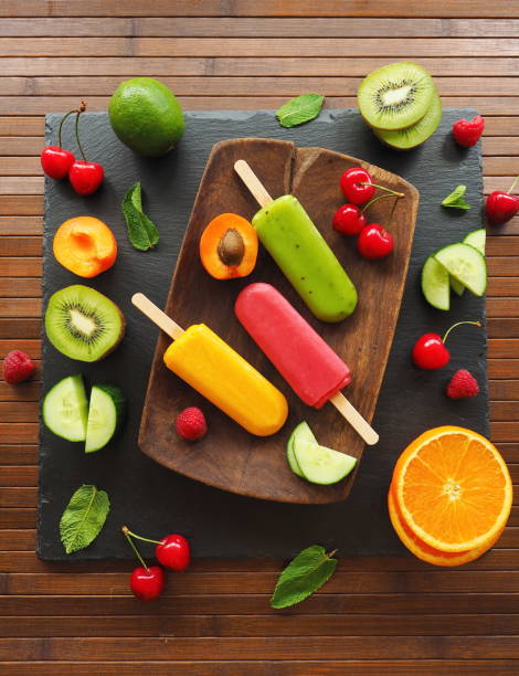 Homemade fruit ice cream - green, red and yellow ones on wooden table