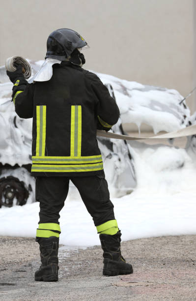 istock firefighter in uniform and hardhat putting out a fire on a crashed car with foam after accident 1314191427