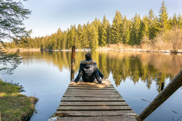 istock Young man standing close to beautiful lake 1314197493