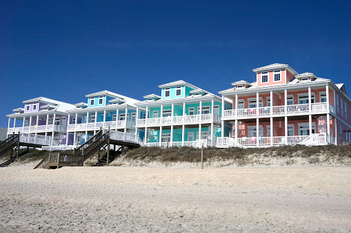 Colorful beach houses on a sandy beach under a blue sky on the North Carolina coast