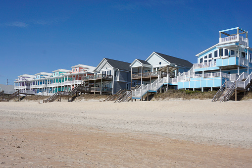 Colorful beach houses on a sandy beach under a blue sky on the North Carolina coast