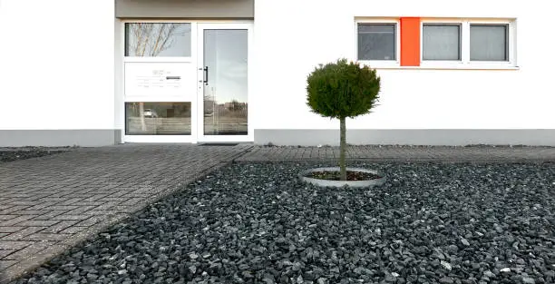 Photo of Front yard at new apartment building with gray gravel stones and a lone small tree