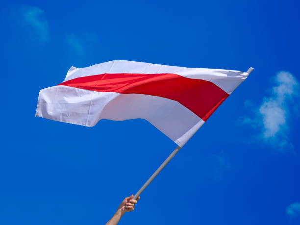 istock Isolated waving Belarusian national flag on blue sky background with clouds. White-red-white flag. 1314205478