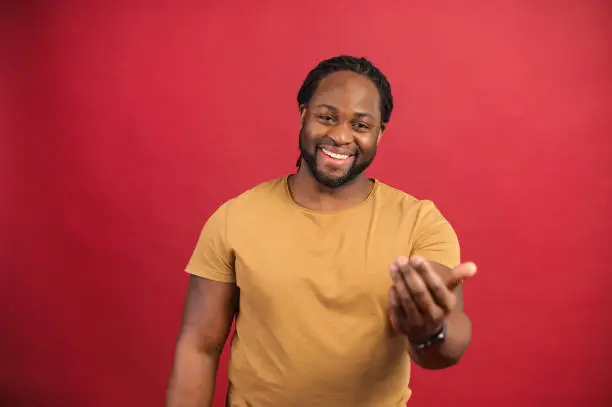 Photo of Cheerful African-American guy isolated on red