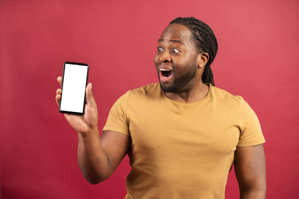 istock Surprised African-American guy holds phone isolated on red 1314206506