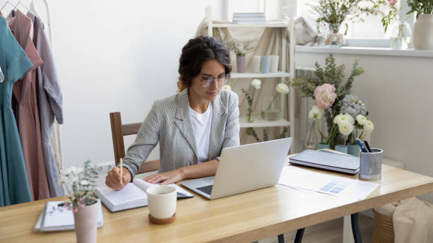 istock Busy female designer sitting by pc making notes in planner 1314206870