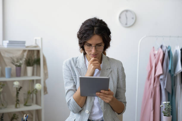 Concentrated millennial self employed businesswoman reading email from tablet screen