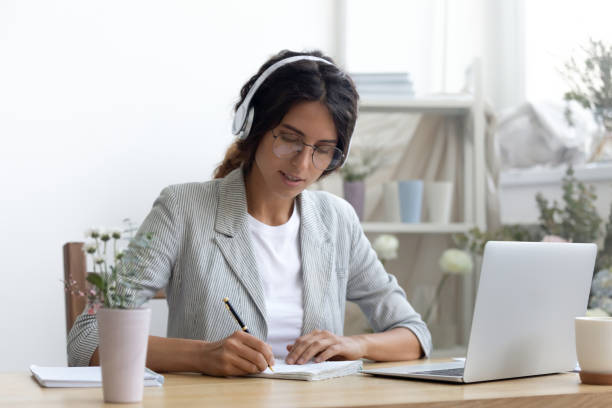 istock Confident woman student studying online in earphones by pc screen 1314206940
