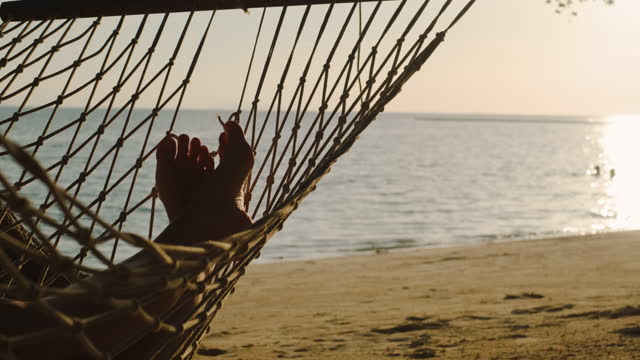 Asian woman resting and sleeping on hammock at beach in summer vacation