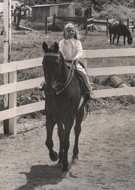 Young Blond Girl Horseback Riding in Hawaii Full length front view of 4 year old Caucasian girl smiling as she and alert horse look at camera on sunny day in Waimanalo. Scanned black and white photograph. oahu photos stock pictures, royalty-free photos & images