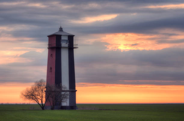 istock Old lighthouse at dawn. Sky background with beautiful clouds and orange sunlight. 1314217154