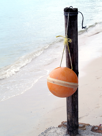 sphere mooring buoy hanging on wooden pole of pier, vertical photo