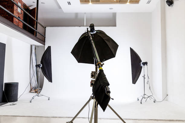 istock Empty photo studio with lighting equipment. Photographer workplace interior with professional tool set gear. Flash light white background scenes ready for studio shooting. Modern photographer studio 1314219748