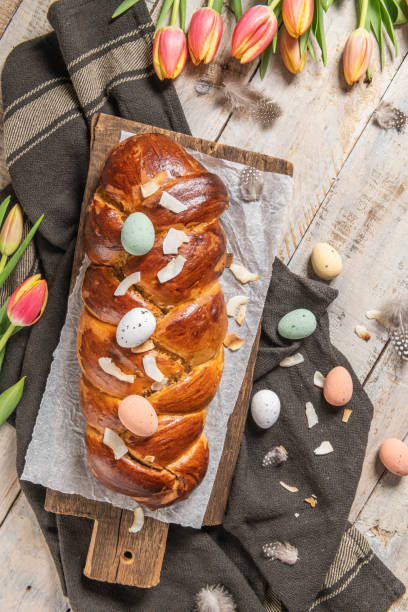 istock Portuguese traditional Easter cake. Folar with eggs on easter table. Blossom tulips, colorful painted eggs and feathers 1314224128