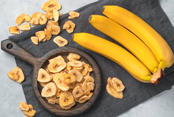 istock Banana chips and fresh bananas on a gray background. Top view 1314225111