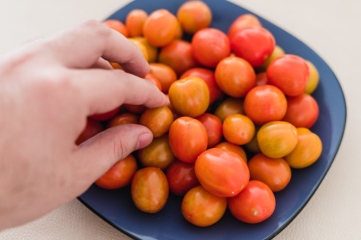 close up shot of a couple cherry tomatoes freshly sow in natural light being groped by a man