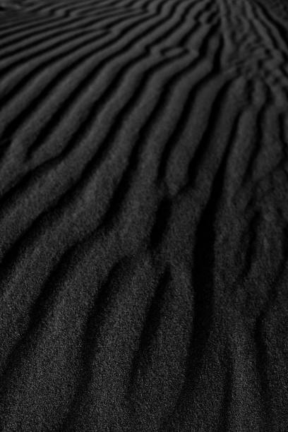 istock Black Sand dune. Black Sand beach macro photography. Background, texture, wave pattern of oceanic sand on the beach, black. Texture of beach sand. Black beach. 1314229883