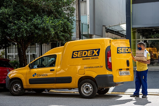 Sao Paulo, Brazil April, 24 - 2021: Logistic van from the Brazilian Post Office. Worker delivers sedex mail with anti covid mask, Brazil. Brazilian government announces privatization of state-owned company