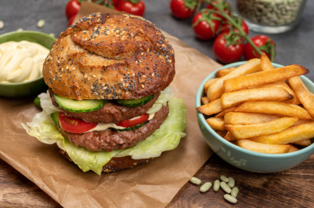 istock Tasty vegetarian vegan lunch with double decker hamburger made from plant based soya beans burger, organic bun with seeds and fresh vegetables and french fried potatoes 1314232861