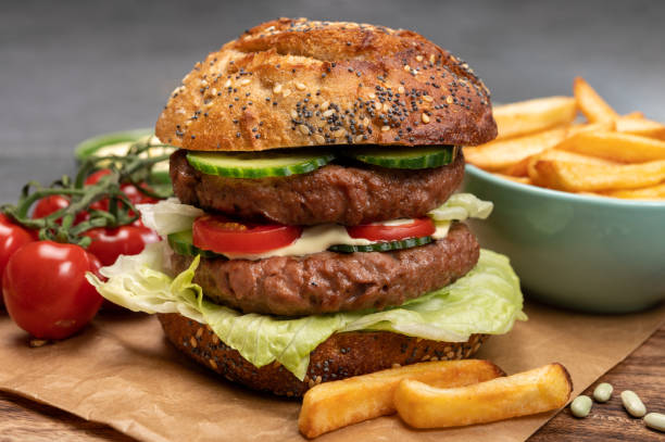 istock Tasty vegetarian vegan lunch with double decker hamburger made from plant based soya beans burger, organic bun with seeds and fresh vegetables and french fried potatoes 1314233790