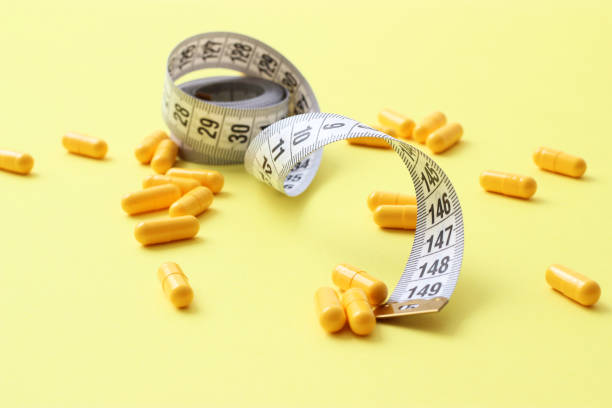 istock Measuring tape and diet pills on a colored background close-up. 1314235803