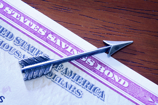 An arrow rests on top of a United States Savings bond.