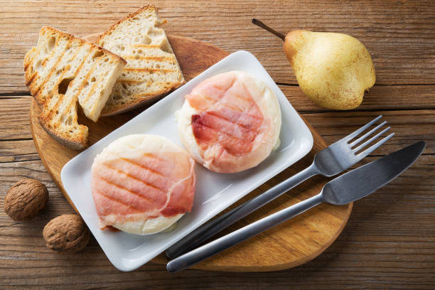 トミーノチーズのスペック(トミーノ・ボスケーロロ)の典型的なイタリアのピエモンテチーズ、パン、クルミ、梨を木製のテーブルに置き、トップビュー。 - tomino ストックフォトと画像