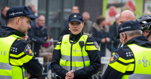Female Dutch police officer talking over the situation with male colleagues stock photo