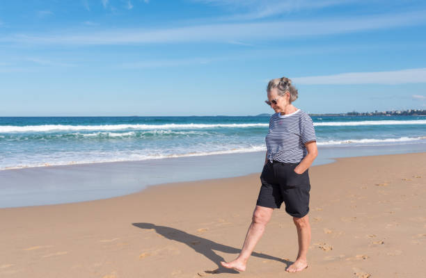 Senior woman walking barefoot at the beach