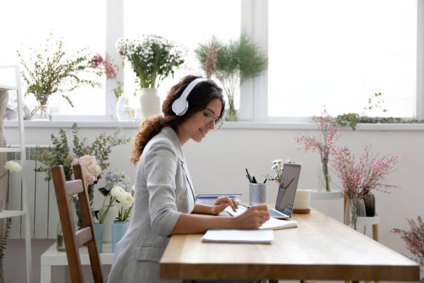 istock Female designer sitting at desk in headset concentrated on paperwork 1314244640