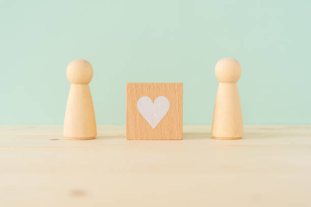Mutual love; A wooden blocks with heart mark and two human toys. Mutual love; A wooden blocks with heart mark and two human toys. coordination photos stock pictures, royalty-free photos & images