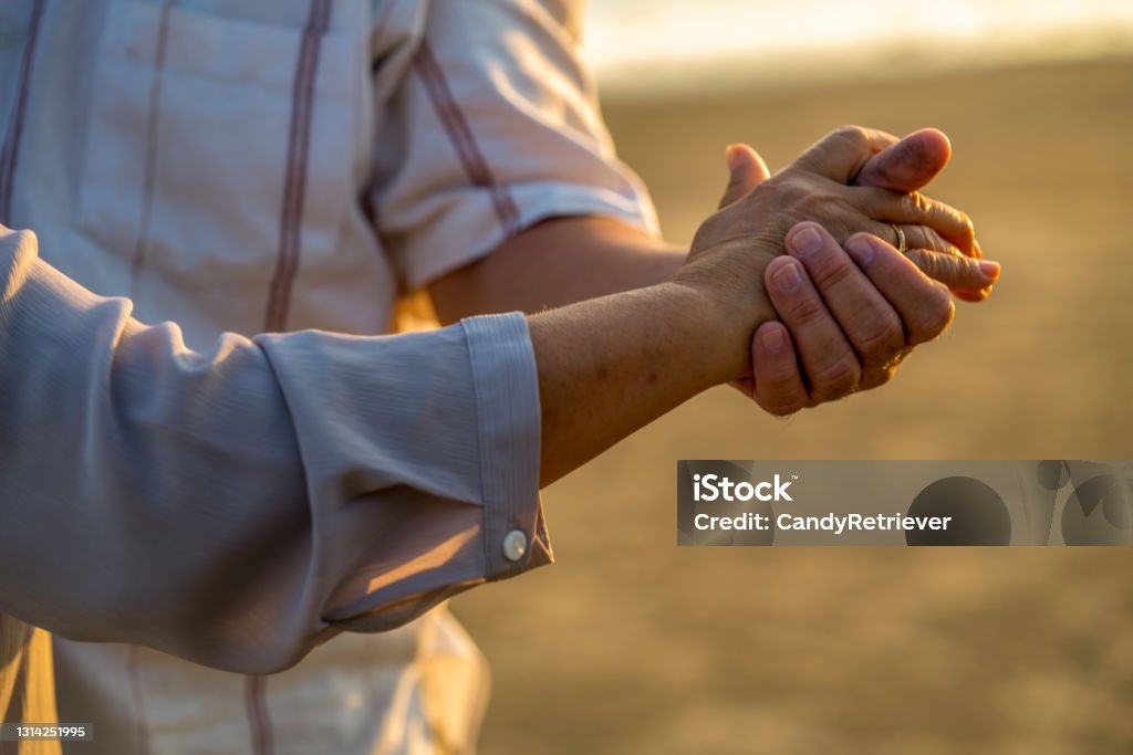 Close up senior couple husband and wife holding hands together on the beach at summer sunset Close up elderly husband and wife holding hand together with love and trust. Healthy retirement senior couple relax and enjoy outdoor activity lifestyle. Happy Asian family on beach vacation concept. Senior Couple Stock Photo