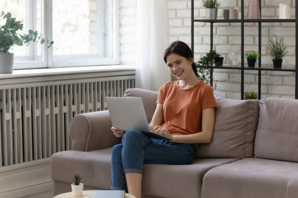 istock Happy young woman sit on couch relaxing with laptop 1314252945