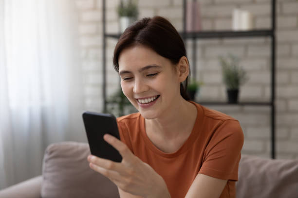 istock Young female sit on sofa hold phone read love message 1314252972