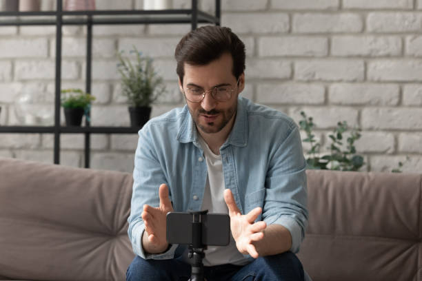 istock Confident male coach sit on sofa before smartphone record training 1314253039