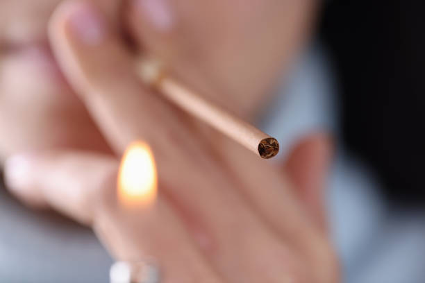 istock Young woman holding cigarette in her hands and setting it on fire 1314253892