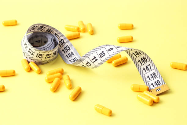 istock Measuring tape and diet pills on a colored background close-up. 1314256356