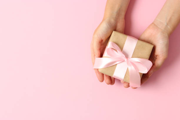istock gift in female hands on a colored background top view. 1314258098