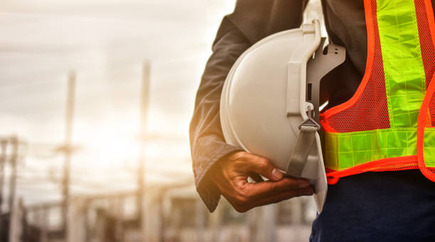 Technician holding white hat safety hard hat sunlight background Technician holding white hat safety hard hat sunlight background safety stock pictures, royalty-free photos & images