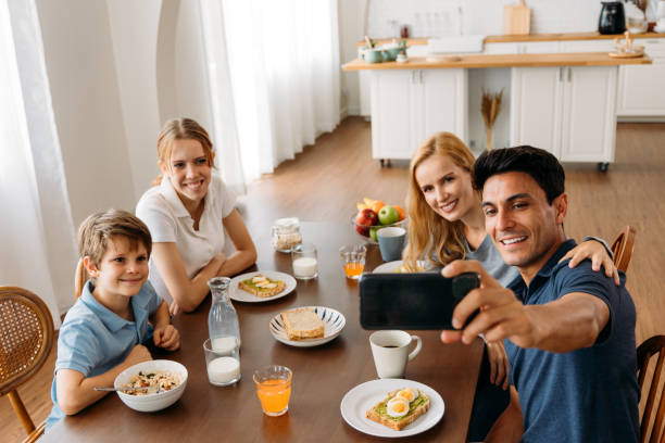 istock Family group taking a photo with smart phone while eating breakfast 1314260380