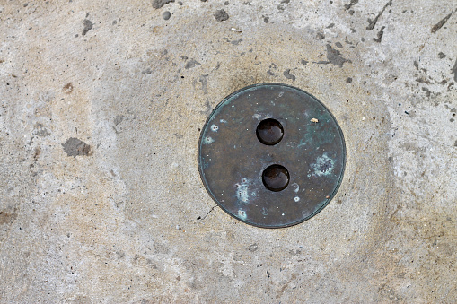 The circular manhole cover made of steel is rusting.