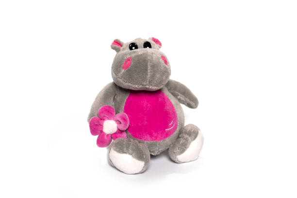 A cute, soft plush rhino toy sits on a clean white surface against a gentle blue background. This adorable animal figure evokes childhood innocence and playfulness in a minimalist studio setting.