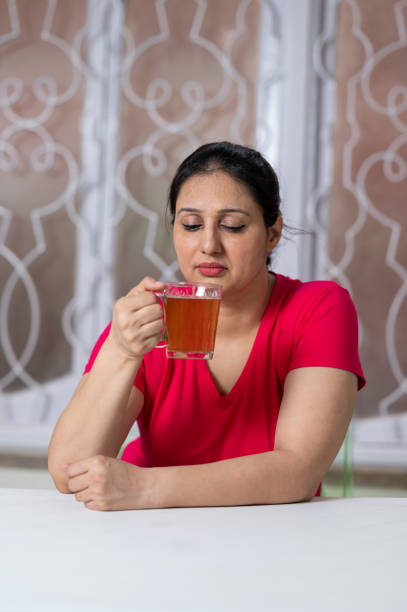 Happy woman taking green tea after morning exercise in house. Happy Asian/ Indian woman taking green tea after morning exercise in house. tea leaves stock pictures, royalty-free photos & images