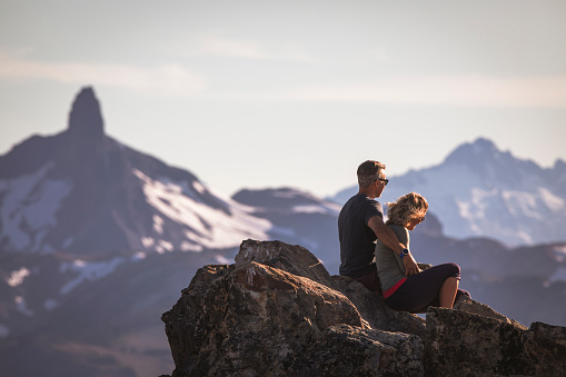 Couple sitting on rocks, looking at views from Whistler alpine.